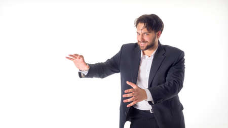 Happy smiling young man with a phone presenting and showing your text or product isolated on white backgroundの写真素材