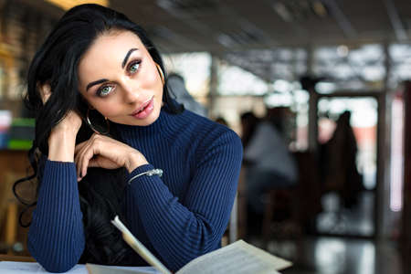 young woman reading a book in a cafeの写真素材