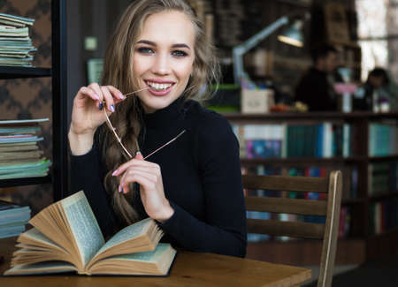 smiling student girl at the library studying with books