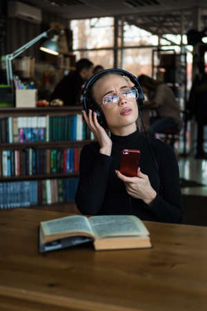 portrait of a college student studying and enjoy listening music in library with a headphonesの写真素材