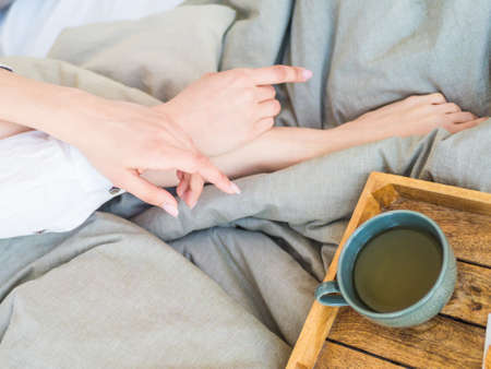 coffee in bed. shapely female legs in warm socks, wooden tray for breakfast in bed. two cups of...