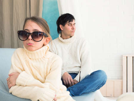 evil father and offended daughter are sitting on the couchの写真素材