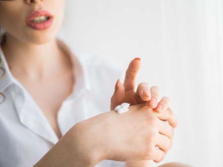 closeup of female hands applying hand cream.