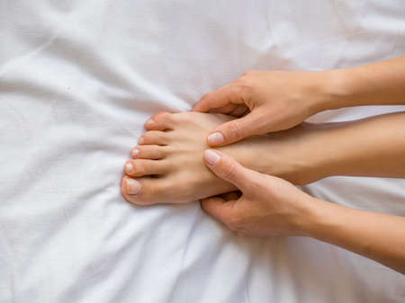 Young woman massaging her foot on the bed., Healthcare concept