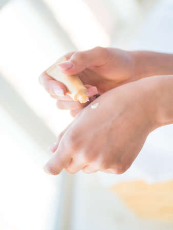Women's hands with pink manicure applying cream. The concept of skin careの写真素材