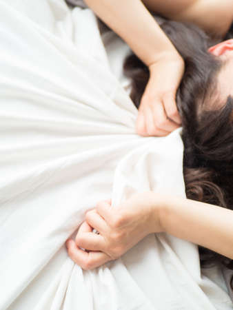 Female hand pulling white sheets in ecstasy, orgasm.