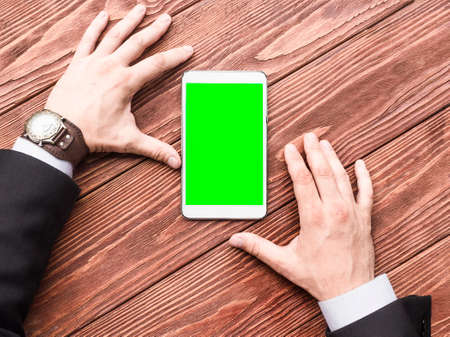 A top view of a hands of a businessman with a tablet PC on the wooden table.