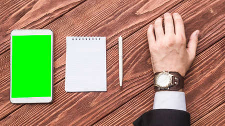 A top view of a hand of a businessman with a tablet PC and notebook on the wooden table.の写真素材