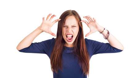 Mad furious young woman with raised hands standing and screaming over white background