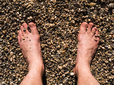 Two male white feet sunbathed on the sand of the beachの写真素材