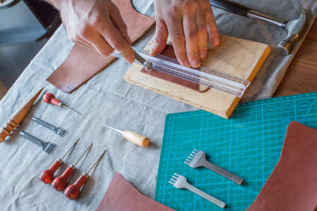 Craft man is working on his leather craft, making vintage leather bag by leather work tool.