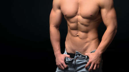Hot young man wearing jeans over black background.