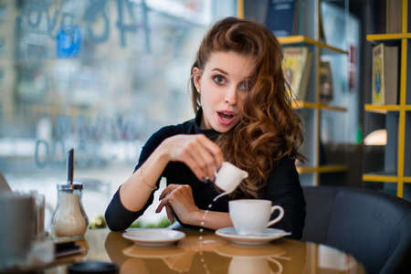 Woman being surprised at cup spilling. Looks at camera.の写真素材