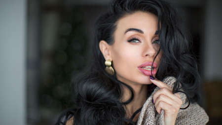 Fashion beauty trend portrait of beautiful brunette girl with long and shiny curly hair. Sexy baby faced model woman with curls hairstyle. Care and beauty of hairの写真素材