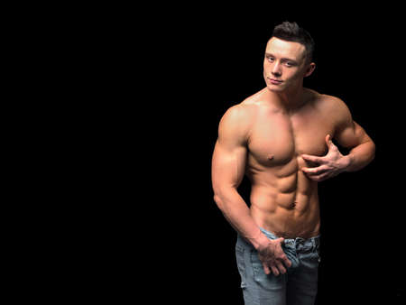 Handsome man with muscular torso on dark background.