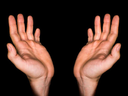 Low key, close up of hands of a faithful mature man praying, hands folded, interlaced fingers in...