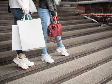 Two woman walk on the street with shopping bagsの写真素材