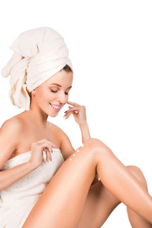 Young woman applying body lotion over white background.の写真素材