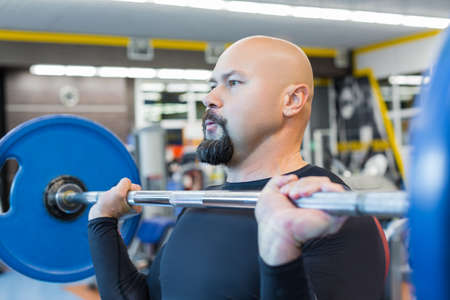 Portait of a brutal middle aged man lifting a barbell in gym.の写真素材