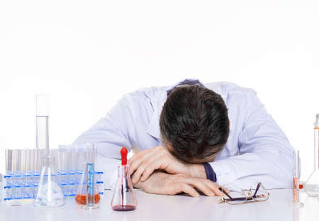 Tired doctor in laboratory put his head on hands.の写真素材