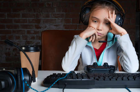 Girl sitting in front of monitor with video game with sad face.の写真素材