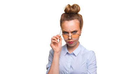 Dissatisfied girl with glasses looking at the camera over glasses.