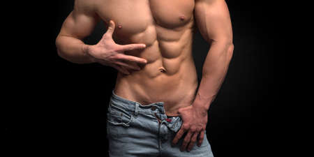 Cropped photo of a sporty man with muscular body in jeans posing in studio