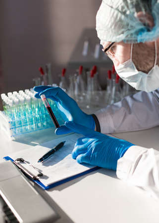 Hands of a doctor in a lab. Making a notes in researching anti-virus vaccine.