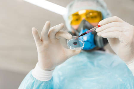Bottom view of a researcher in a lab dripping a blood sample in a Petri dish.の写真素材