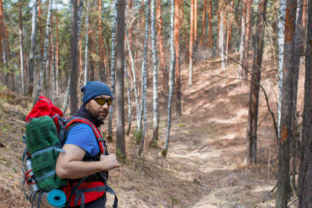 Male tourist with a backpack in the forest. Close up portrarit.