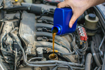 Close up photo of a male hand pouring an oil into a car engine.の写真素材
