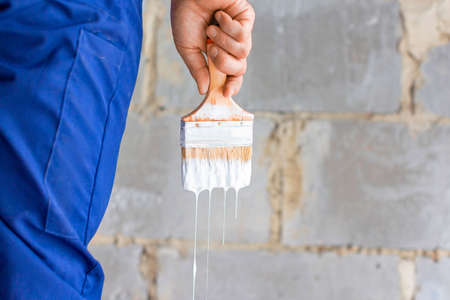 Detail shot of a male hand with a brush in a white paint.の写真素材