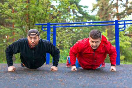 Two middle aged athletes doing push ups.