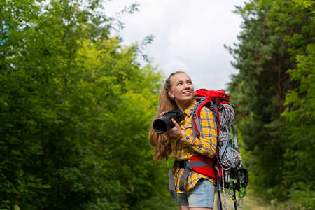 Smiley female hiker woman looking by side and holding photocam.の写真素材