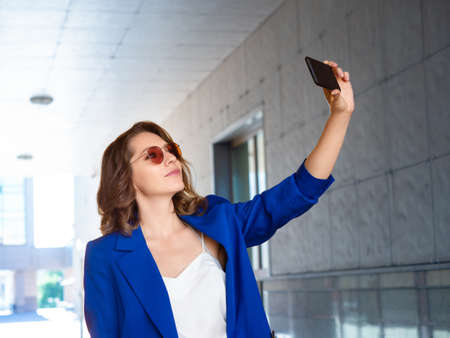 Beautiful businesswoman in eyeglasses takes a selfie.の写真素材