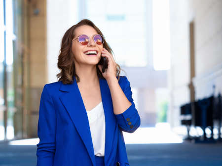 Close portrait of a woman in a business suit smiling talking phone.の写真素材