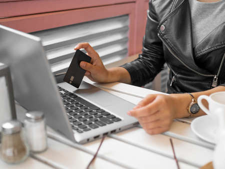 Close-up view of afemale hands with laptop and credit card.
