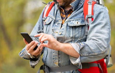Photo of a man using his smartphone like a navigator in a forest.