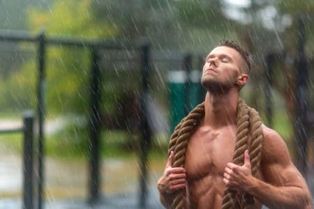 Sportsman having rest after hard workout outdoor in a rainy day. Man with closed eyes relaxing under drops of rain.の写真素材