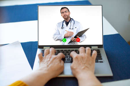 Elderly womans hands behind the laptop keyboard. Online consultation with your doctor.の写真素材