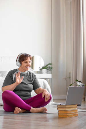 Senior woman in headphones preparing to exercising online.の写真素材
