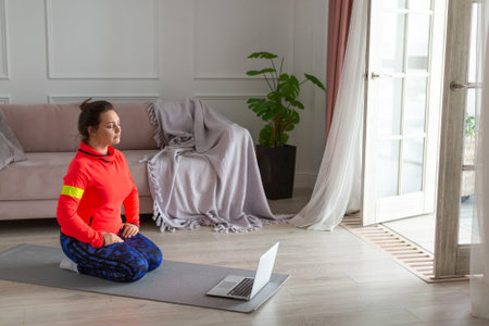 Woman meditate in front of laptop in home interior.の写真素材