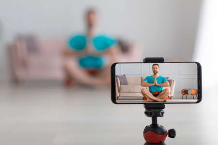 Middle aged man online streaming yoga workout. Live streaming on a smartphone. Focus on smartphone.