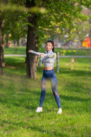 Woman stretching shoulders - warming up before running or working out. Young female runner stretching arms before running at morning.の写真素材