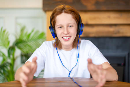 Photo of a red-haired teenager during an online video call. He communicates with friends and...