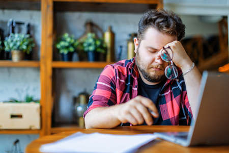 Photo of an exhausted man working at home before the deadline.の写真素材