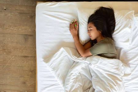 Top view of a sleeping asian woman - she lies under the blanket.の写真素材