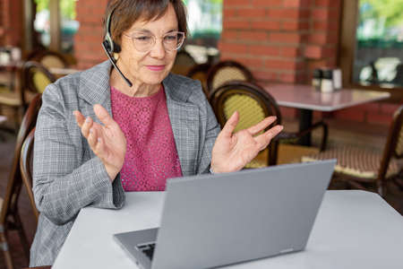 Close up photo of a senior woman during online video call. She i working in front of laptop monitor...