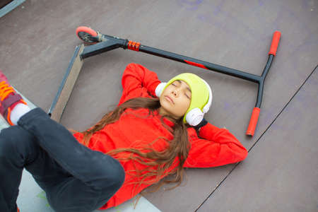 View of a ten-year-old girl is resting after riding a scooter.の写真素材