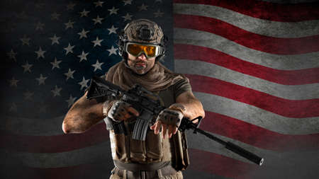 American infantryman stands against a concrete wall with the American flag. Veterans day concept.